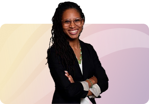 A woman with glasses and long dreadlocks smiling, standing with arms crossed in front of a colorful abstract background.
