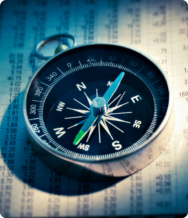 A compass placed on printed financial data, demonstrating navigation or decision-making in financial contexts.