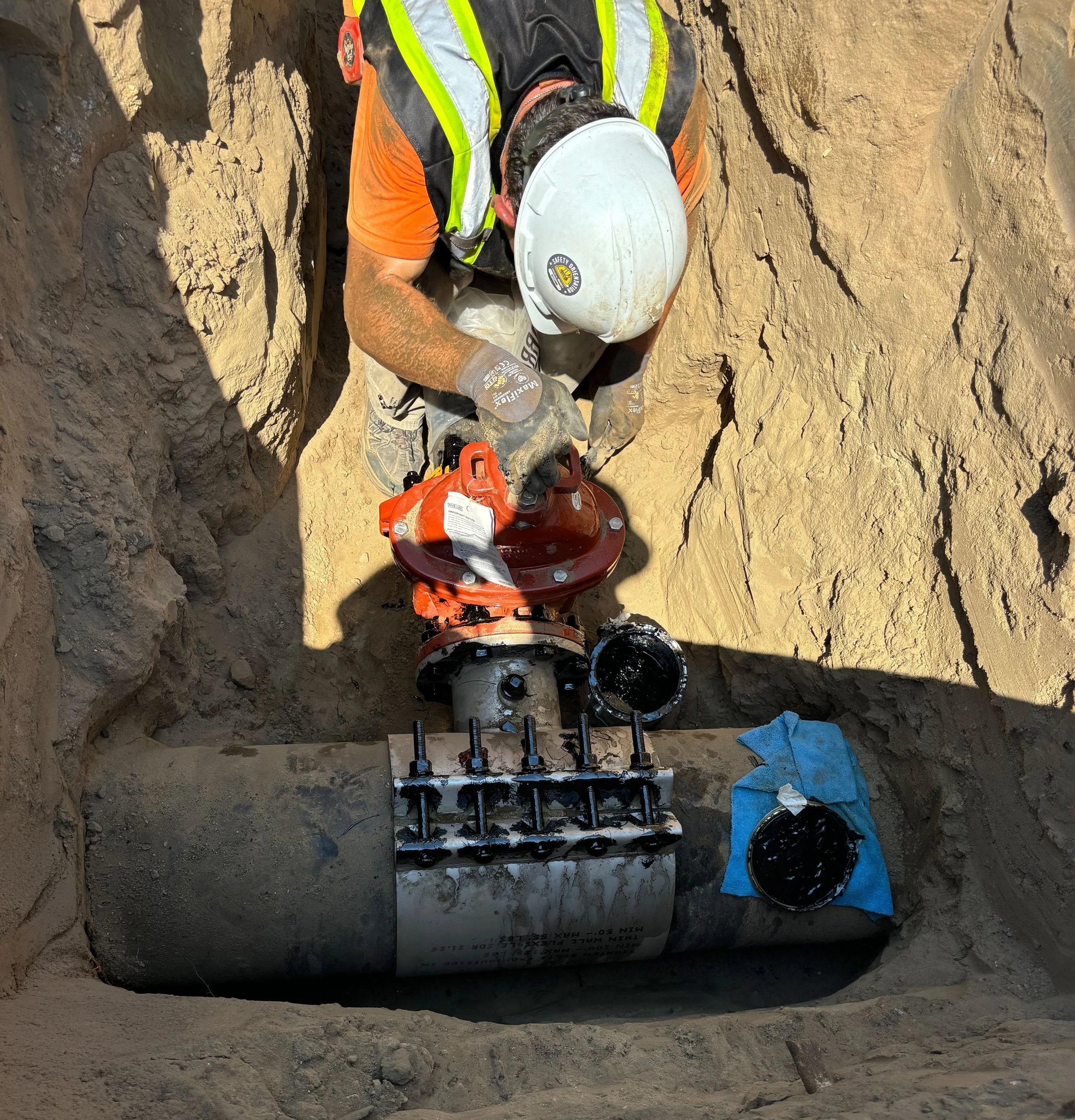 man working on a fire main in an open trench
