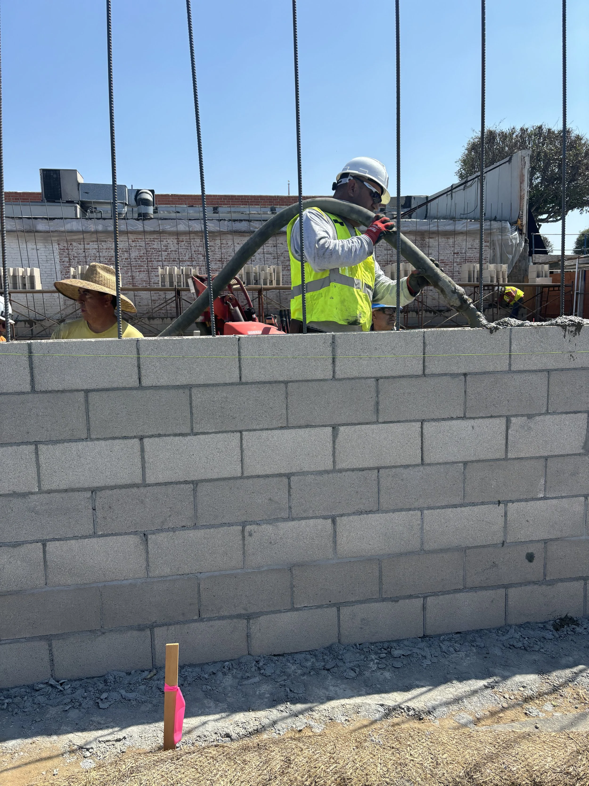 Construction workers pouring concrete on a brick wall project at a construction site.