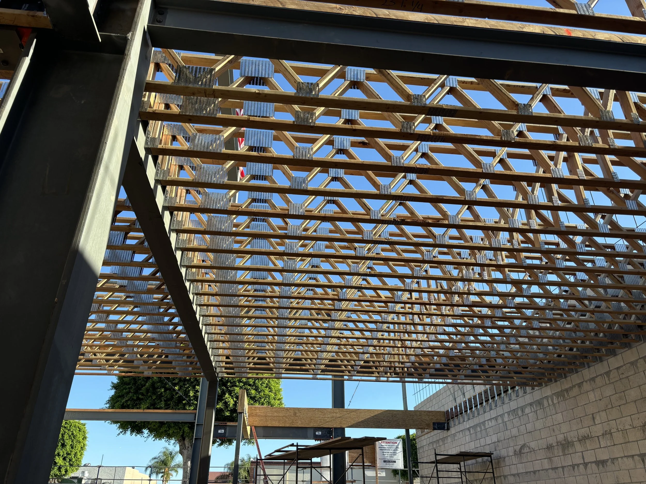 Wooden grid structure construction site with metal supports and blue sky in background.