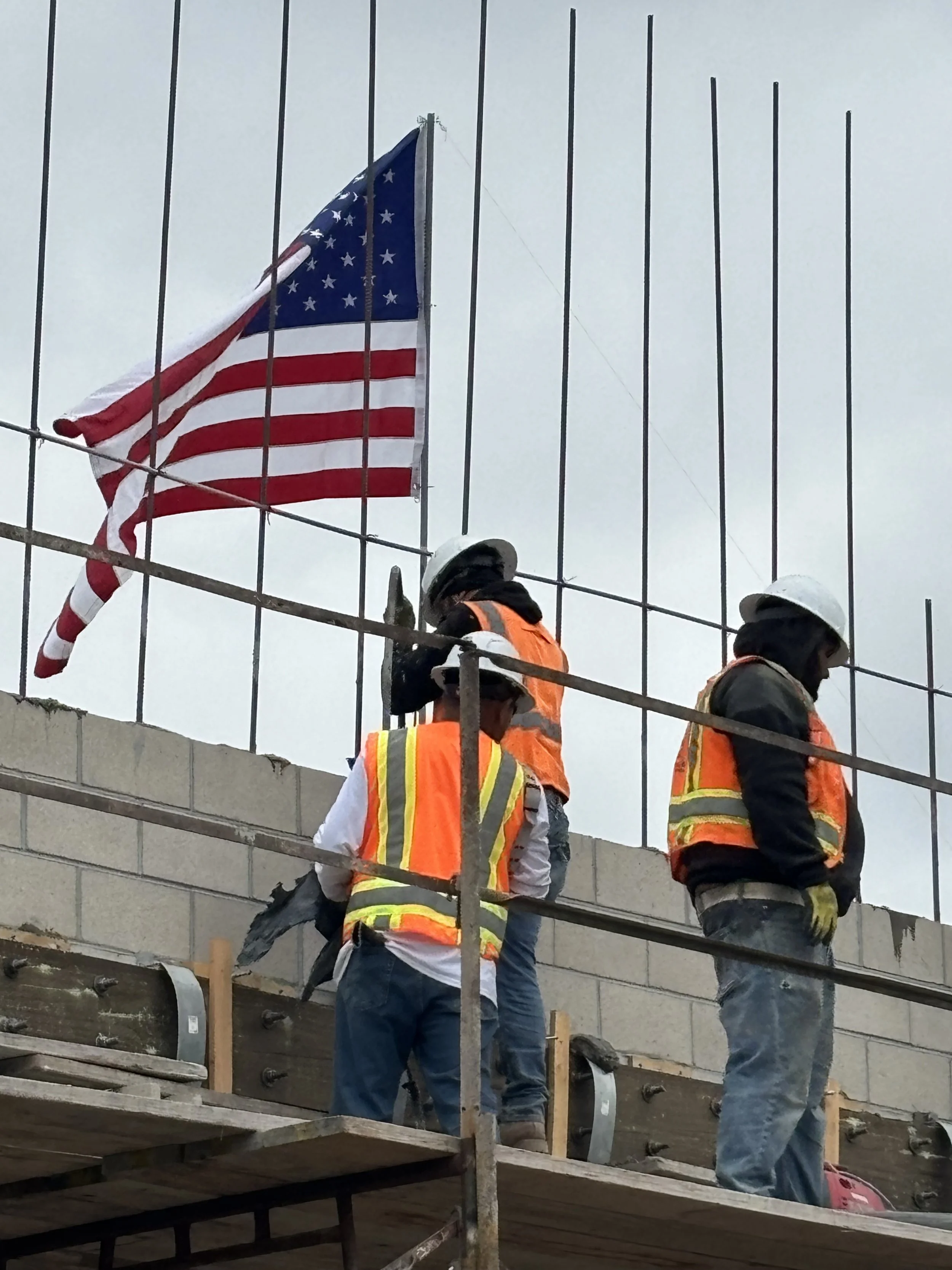 image of construction works erecting an american flag