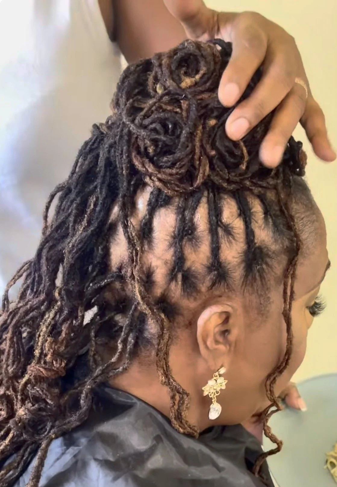 Woman with styled dreadlocks, getting her hair done.