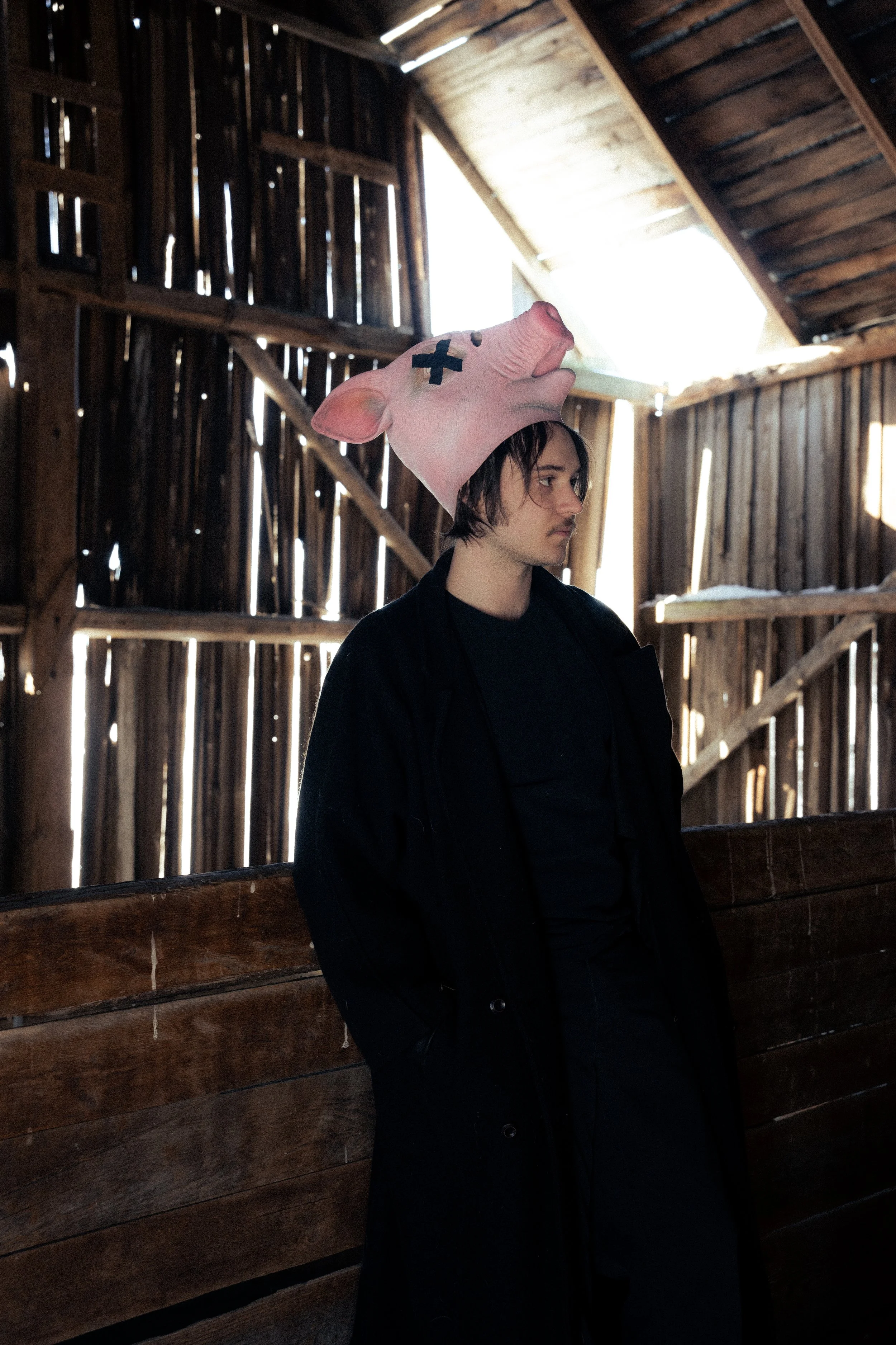 Un jeune homme portant un chapeau de cochon en peluche dans une grange en bois