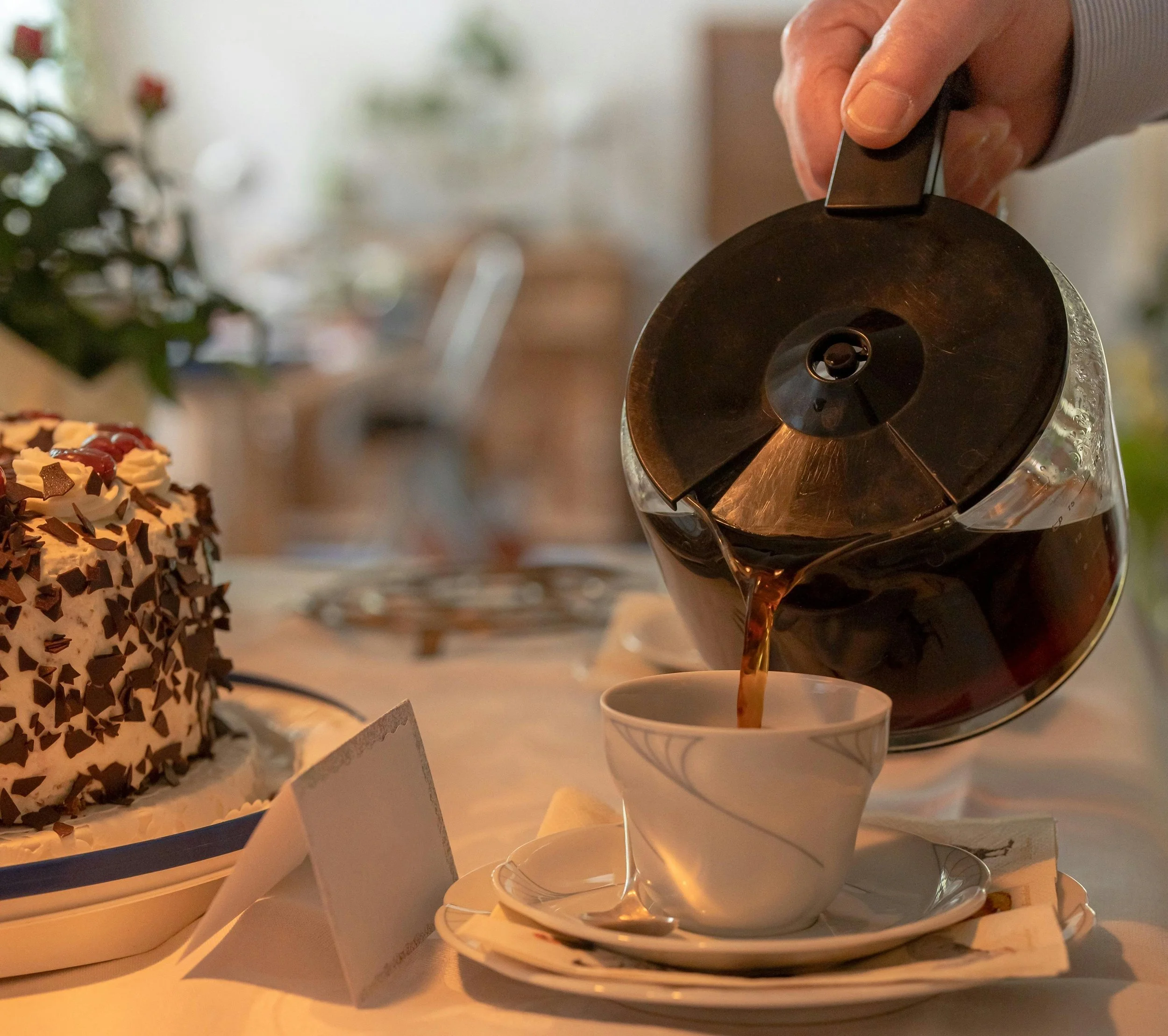 Person pouring coffee at a table with cake representing the complicated relationship with food and enjoyment when living with food sensitivities