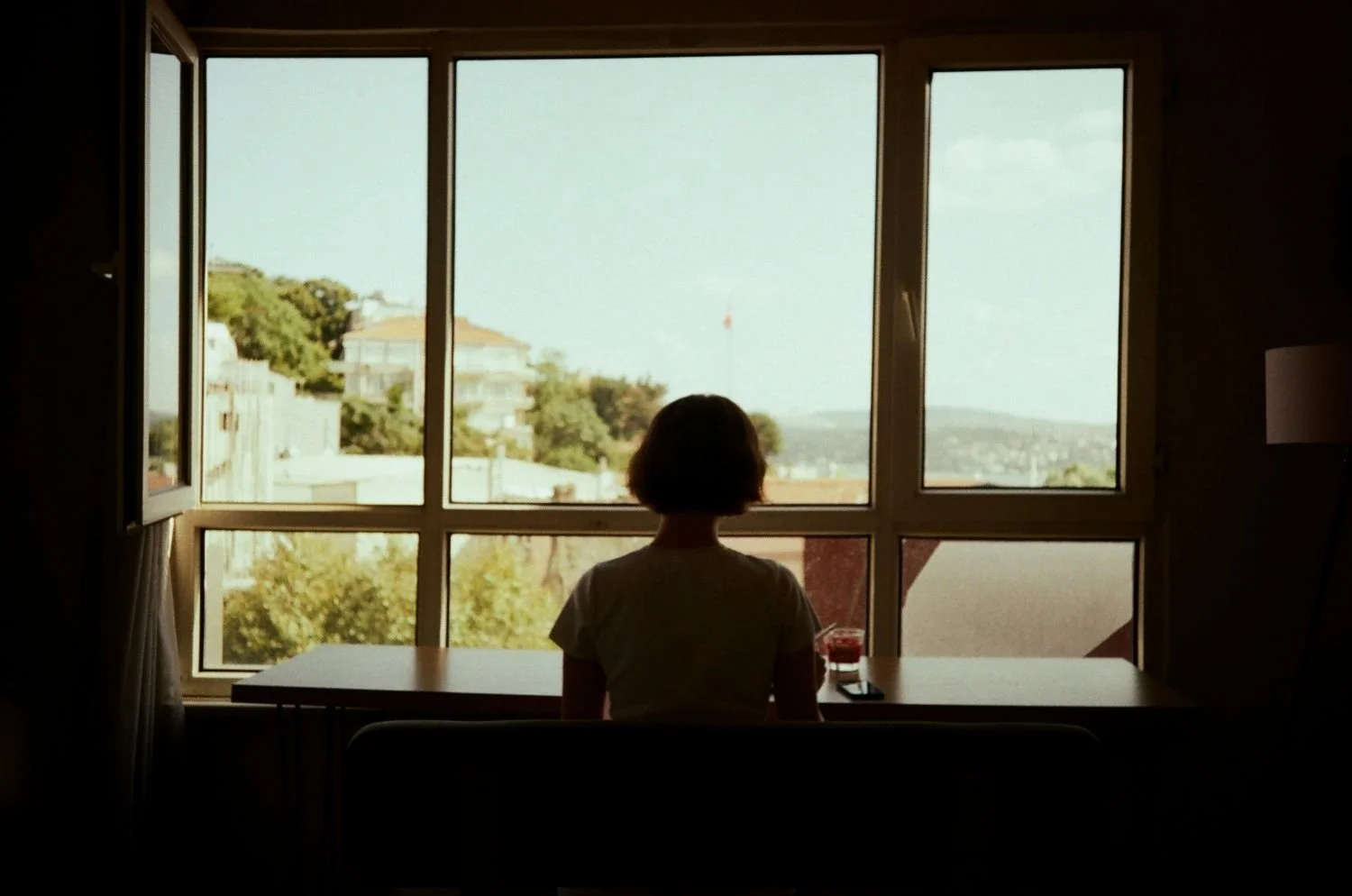 Woman sitting alone at a window, looking out