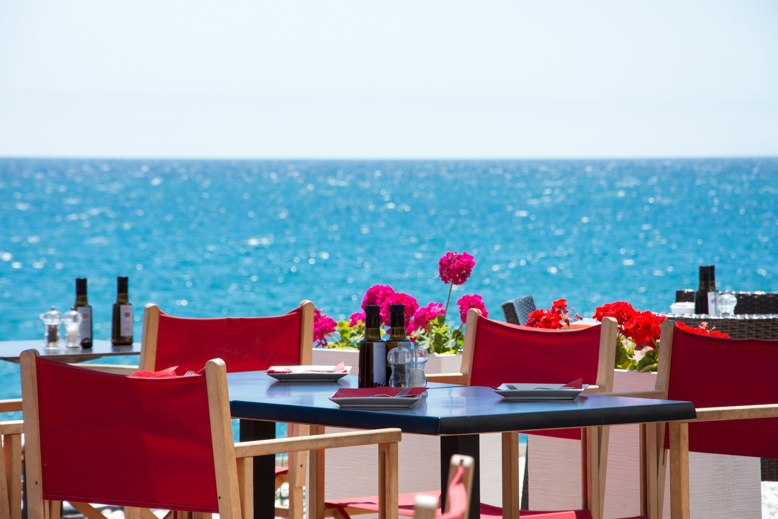 Seafront restaurant table with red chairs representing the challenge of eating out while travelling with food sensitivities