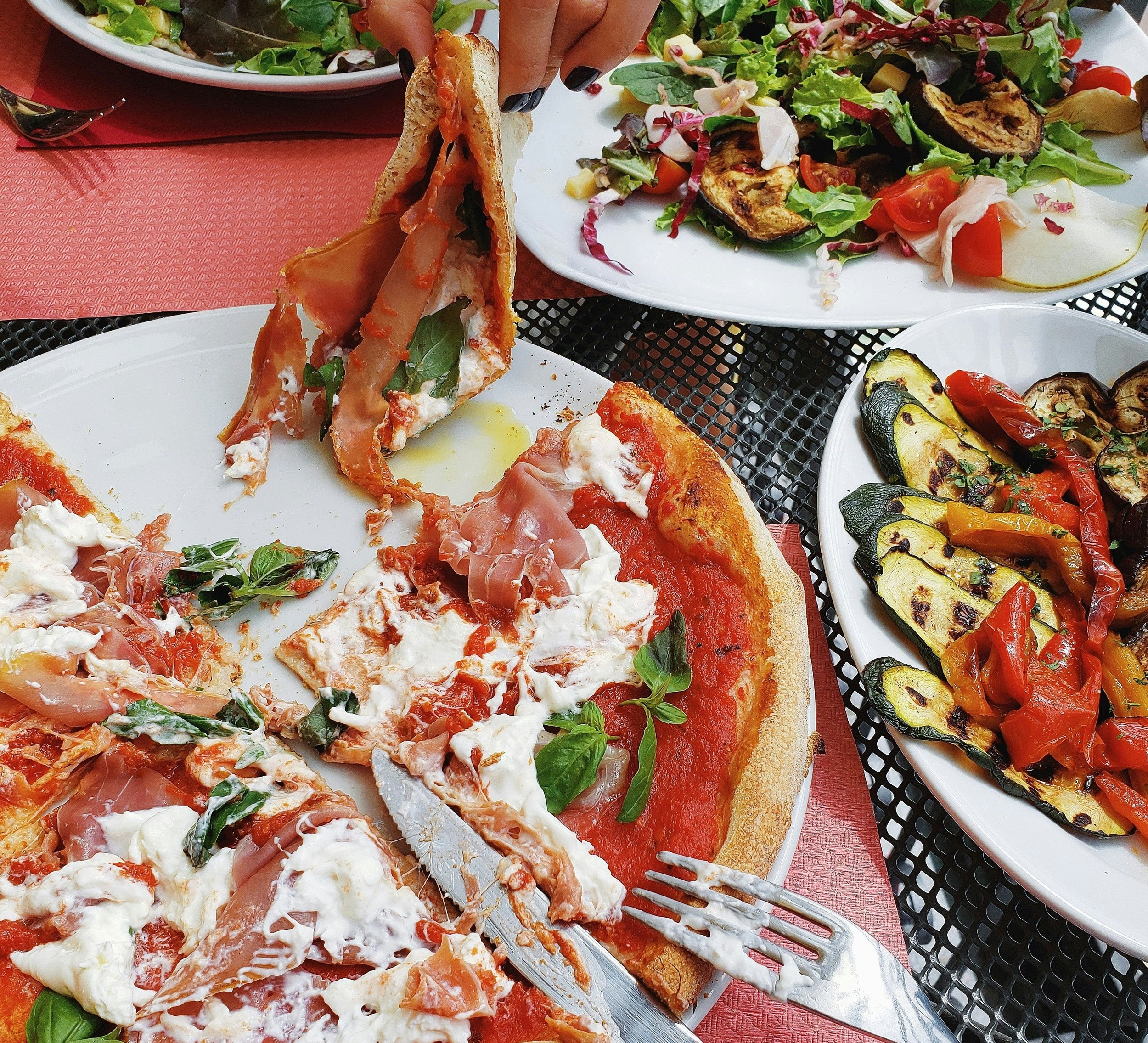 Pizza, salad and grilled vegetables at a restaurant table representing eating freely and what feeling healed means when living with food sensitivities