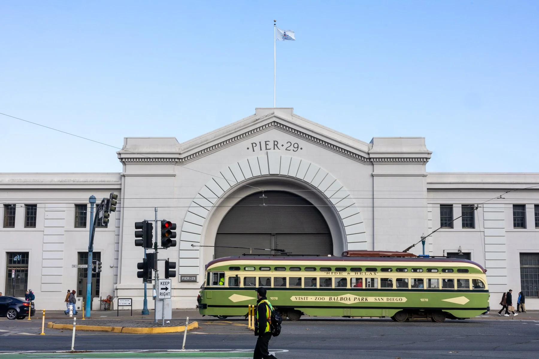 Historic Pier 29 building entrance on San Francisco Embarcadero with vintage green streetcar passing by