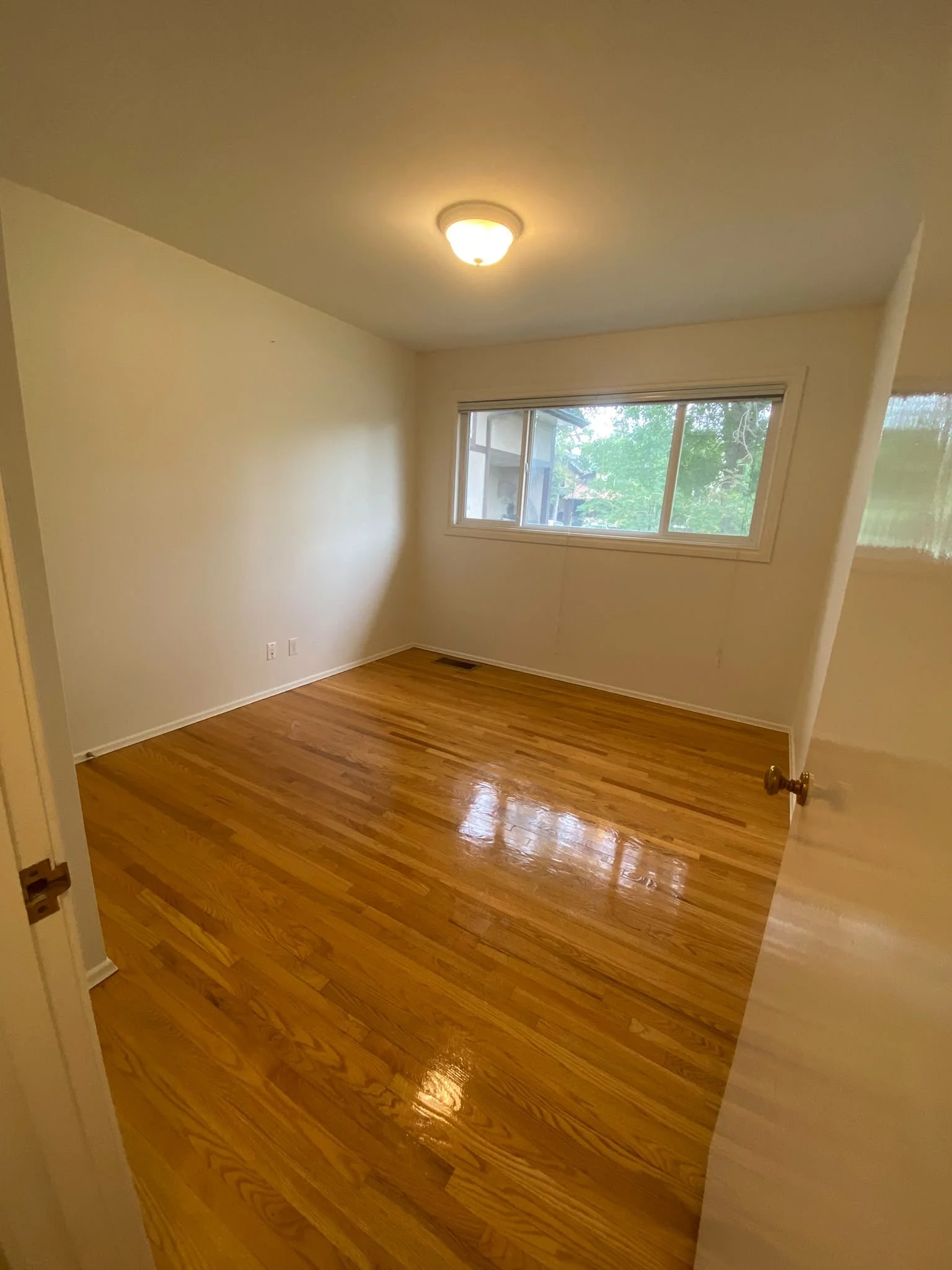Spotless bedroom with polished floors and clean baseboards, cleaned by AAE Home Glow's residential team.