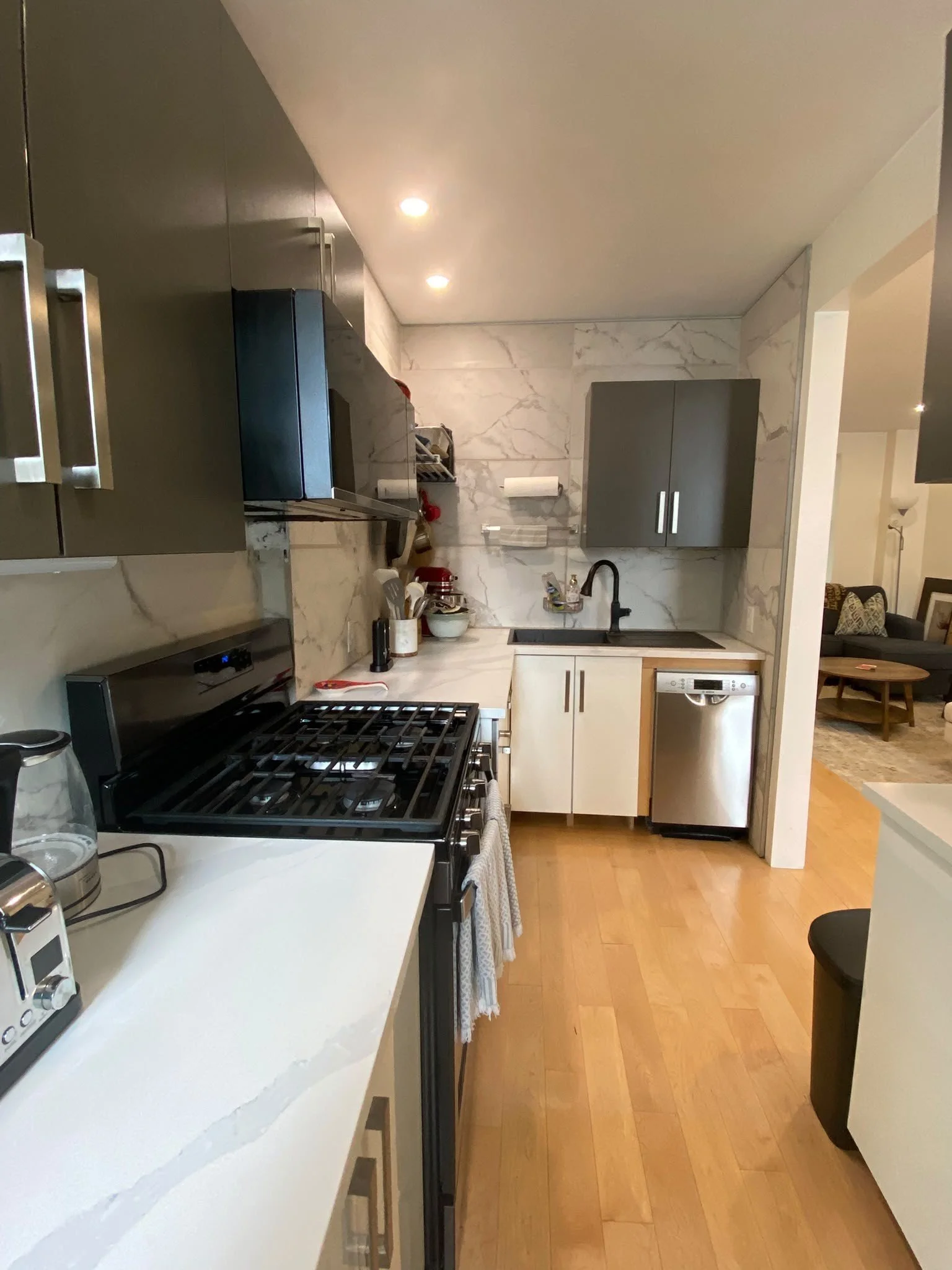 Sparkling clean kitchen after a deep clean by AAE Home Glow, featuring marble backsplash, black cabinets, and stainless steel appliances in a Calgary home.