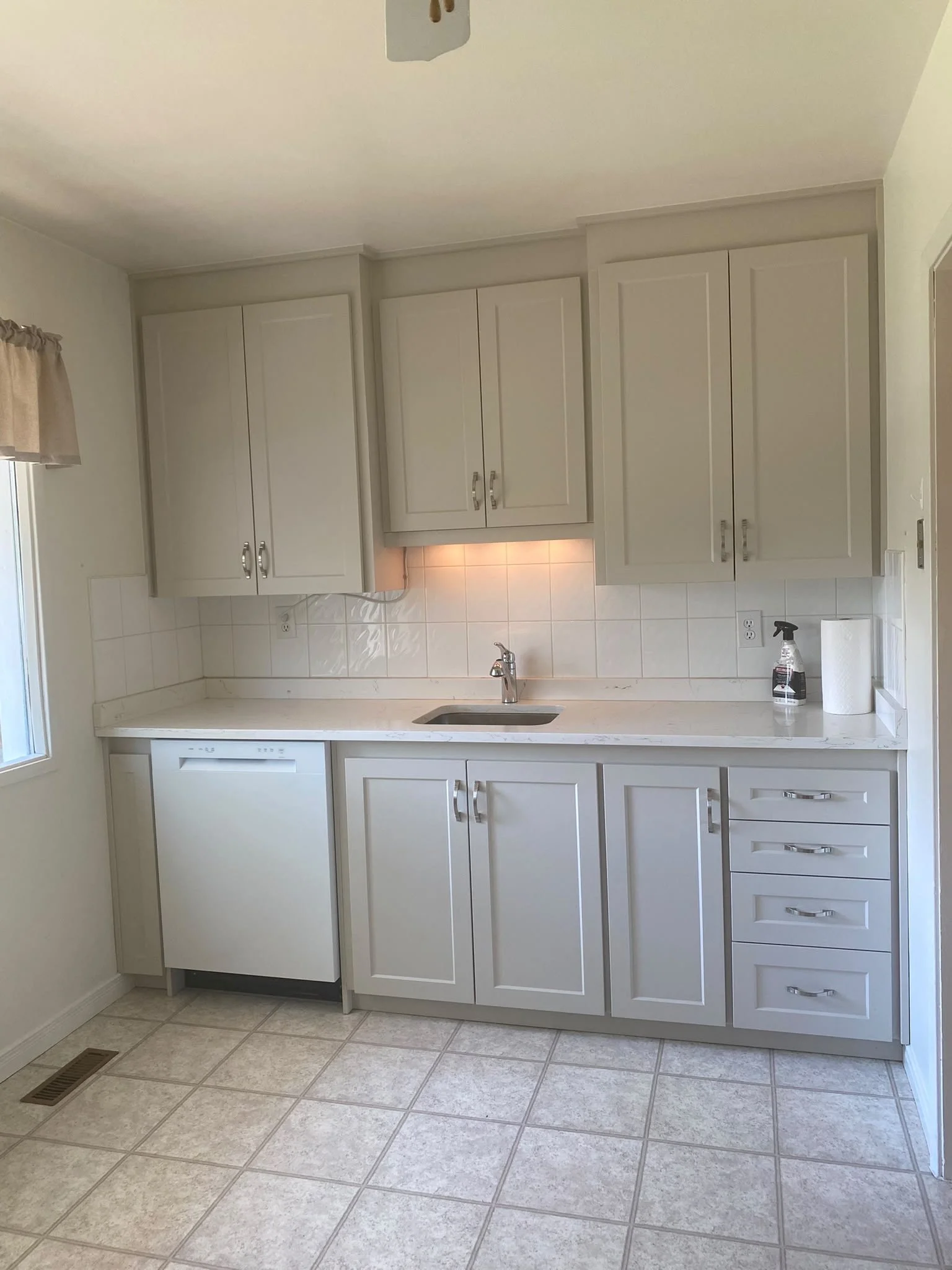 Sparkling clean kitchen after a deep clean by AAE Home Glow, featuring marble backsplash, black cabinets, and stainless steel appliances in a Calgary home.