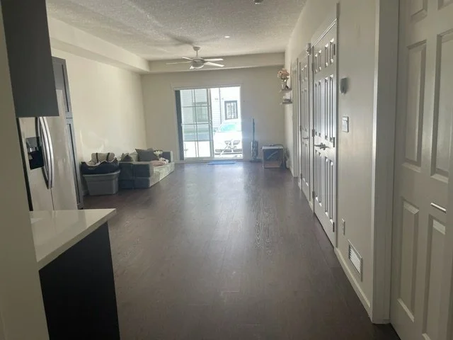 Freshly cleaned living room in a Calgary home, with hardwood floors, a bookshelf, and dining area cleaned by AAE Home Glow's residential cleaning team.
