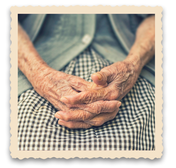 Close-up of elderly person's hands resting peacefully in their lap, wearing checkered clothing.