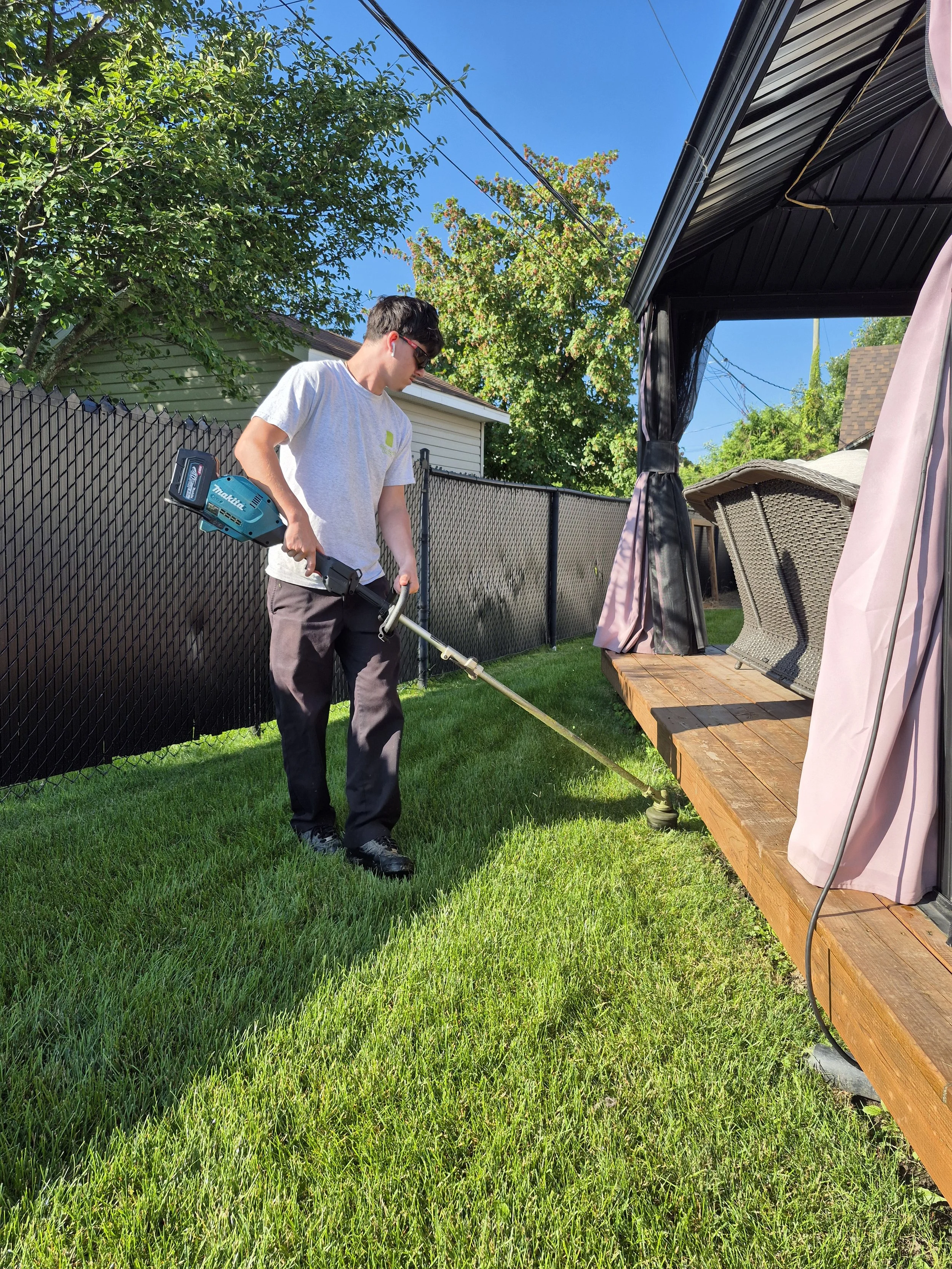 Employé de Guillaume Gazon effectuant la taille des bordures lors d’un entretien de pelouse résidentielle à Saint-Amable