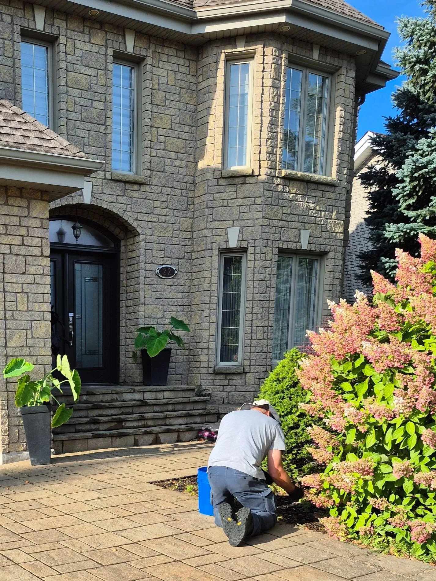 Entretien de plates-bandes réalisé par un employé de Guillaume Gazon devant une résidence sur la Rive-Sud de Montréal