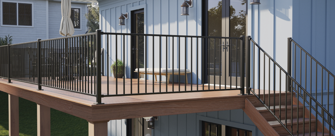 A wooden deck with black metal railing attached to a light blue house, accessed by stairs, with a bench and potted plant on the deck.