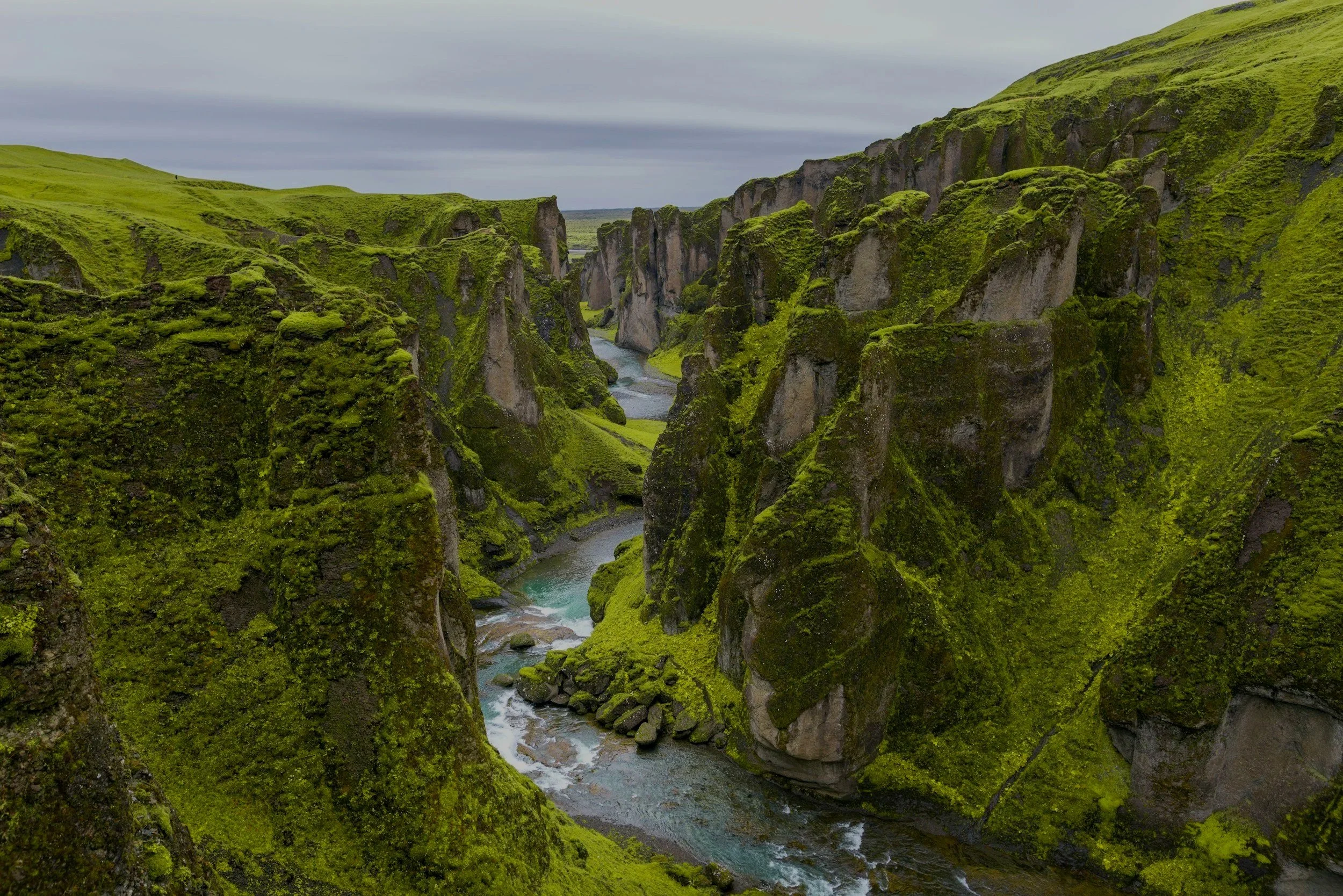 Paisaje natural con cañones verdes y río que fluye entre las rocas.