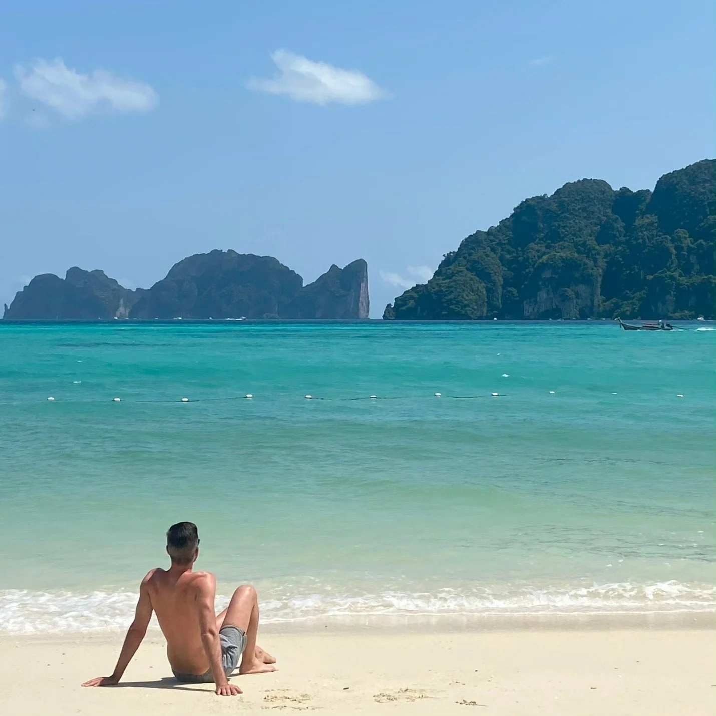 Chico tumbado relajado en una playa de Tailandia, mirando al horizonte
