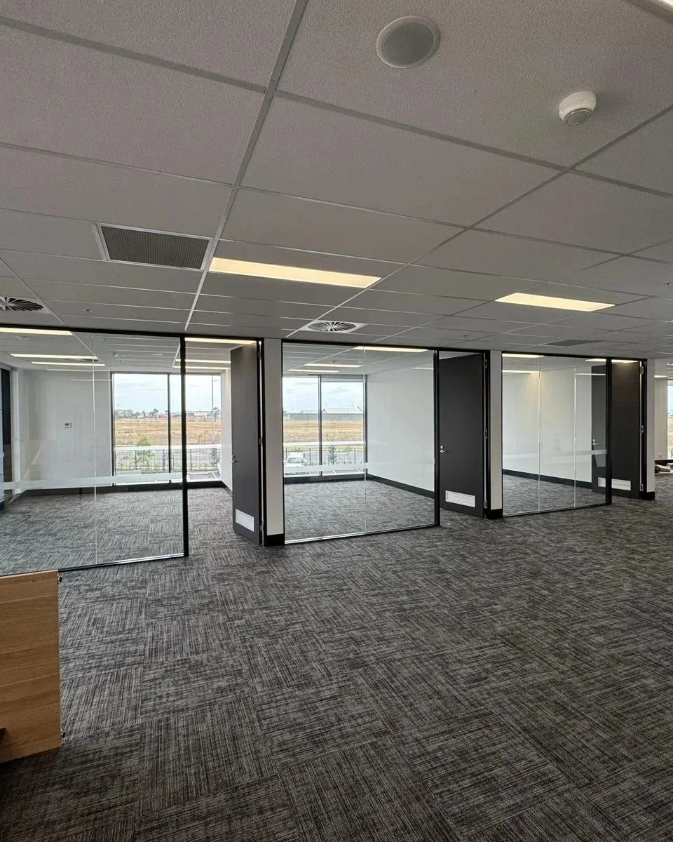 Empty modern office space with glass walls and large windows, view of an open field outside.