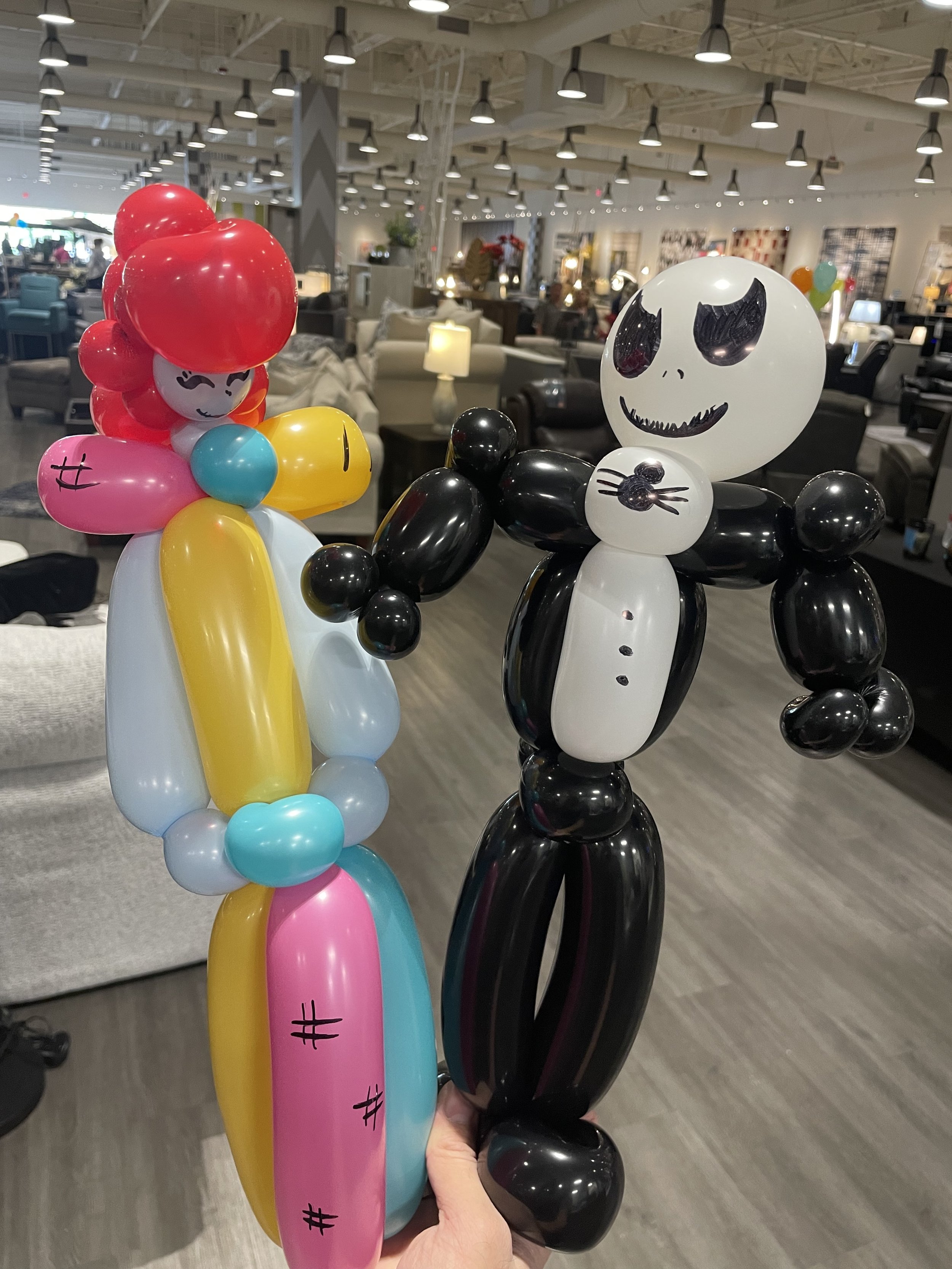 Balloon sculptures of Jack Skellington from 0o Halloween and Sally from 0o Halloween in a furniture store.