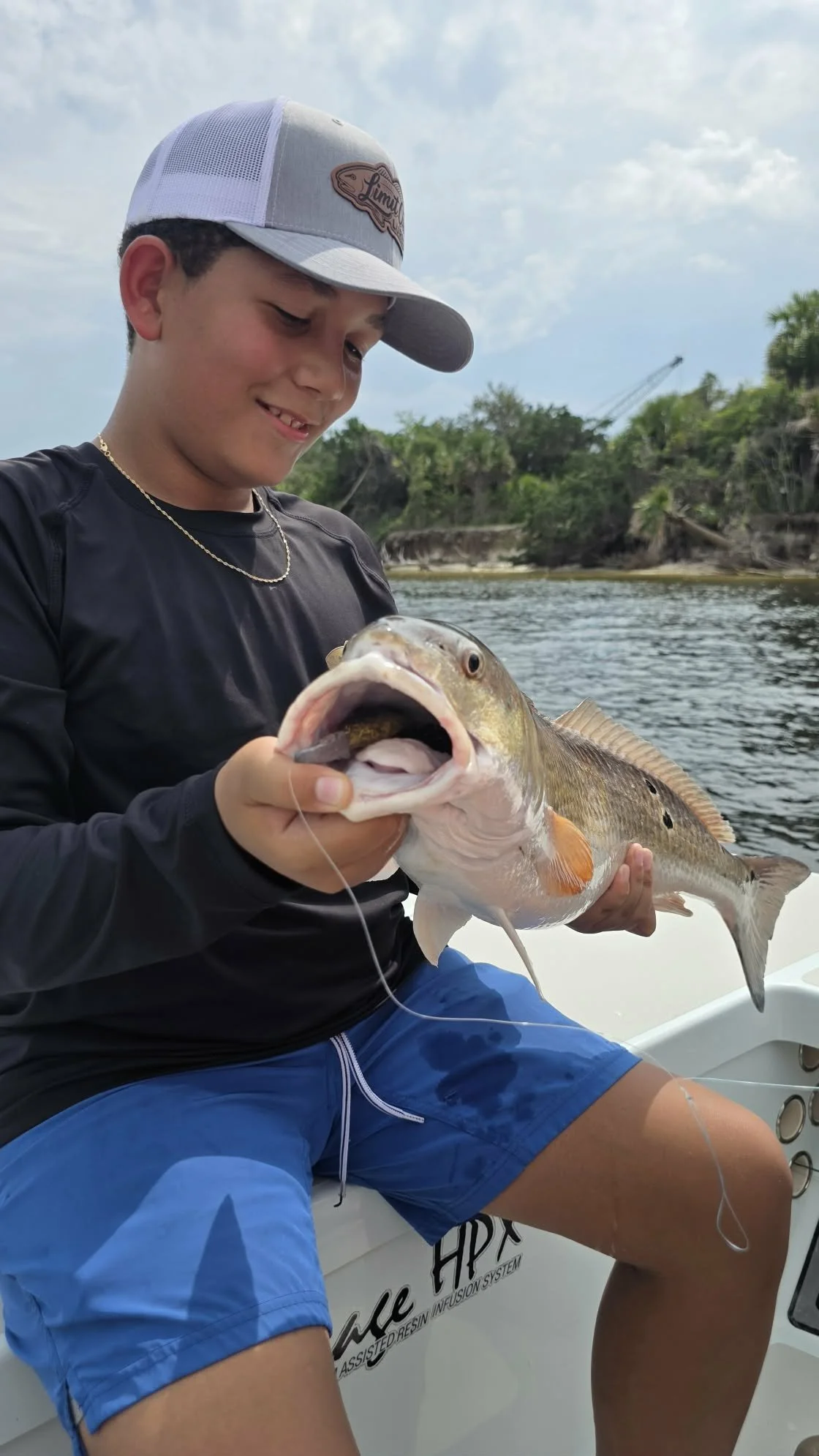 young angler holding a bull redfish he caught off the the coast of Florida on limit out lures 525 magnum paddletail. 