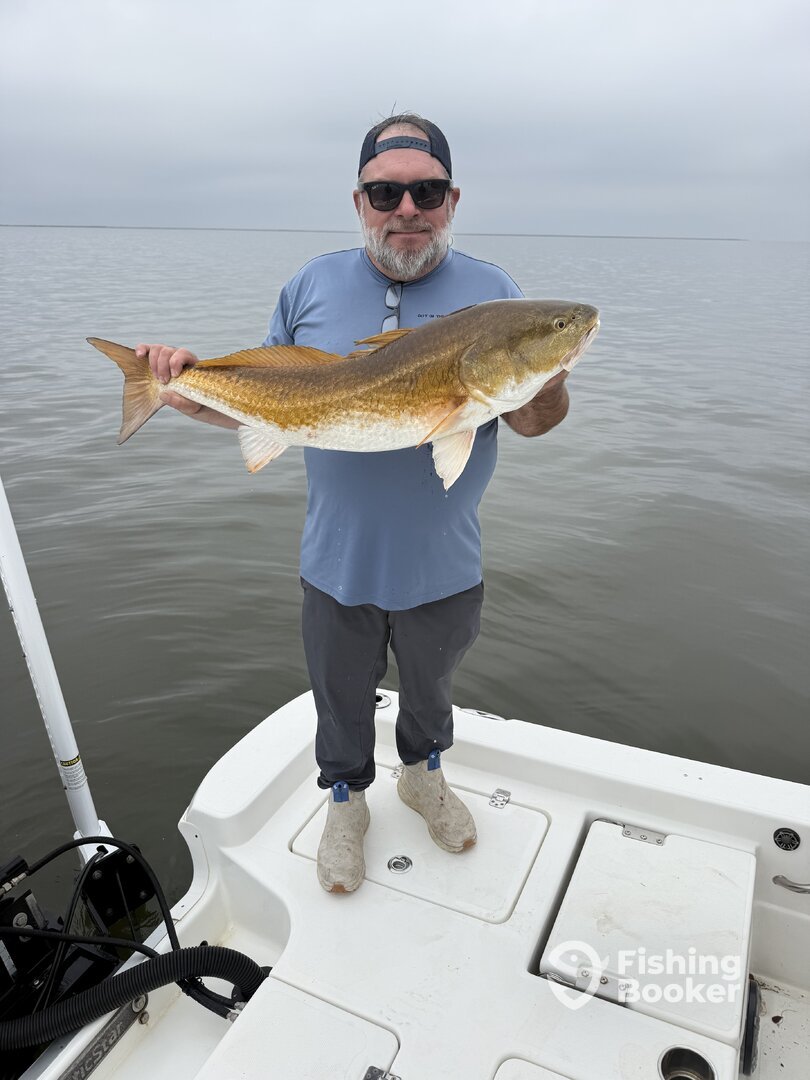 Man Holding Redfish In La Charter Guide Power pole ANchor Fishing boots Monster Fish