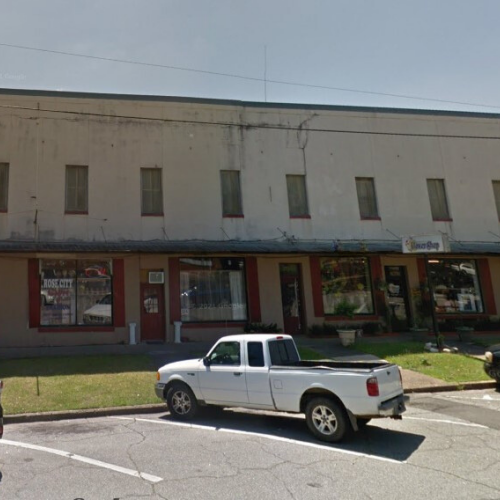 A two-story commercial building with store windows and a white pickup truck parked in front