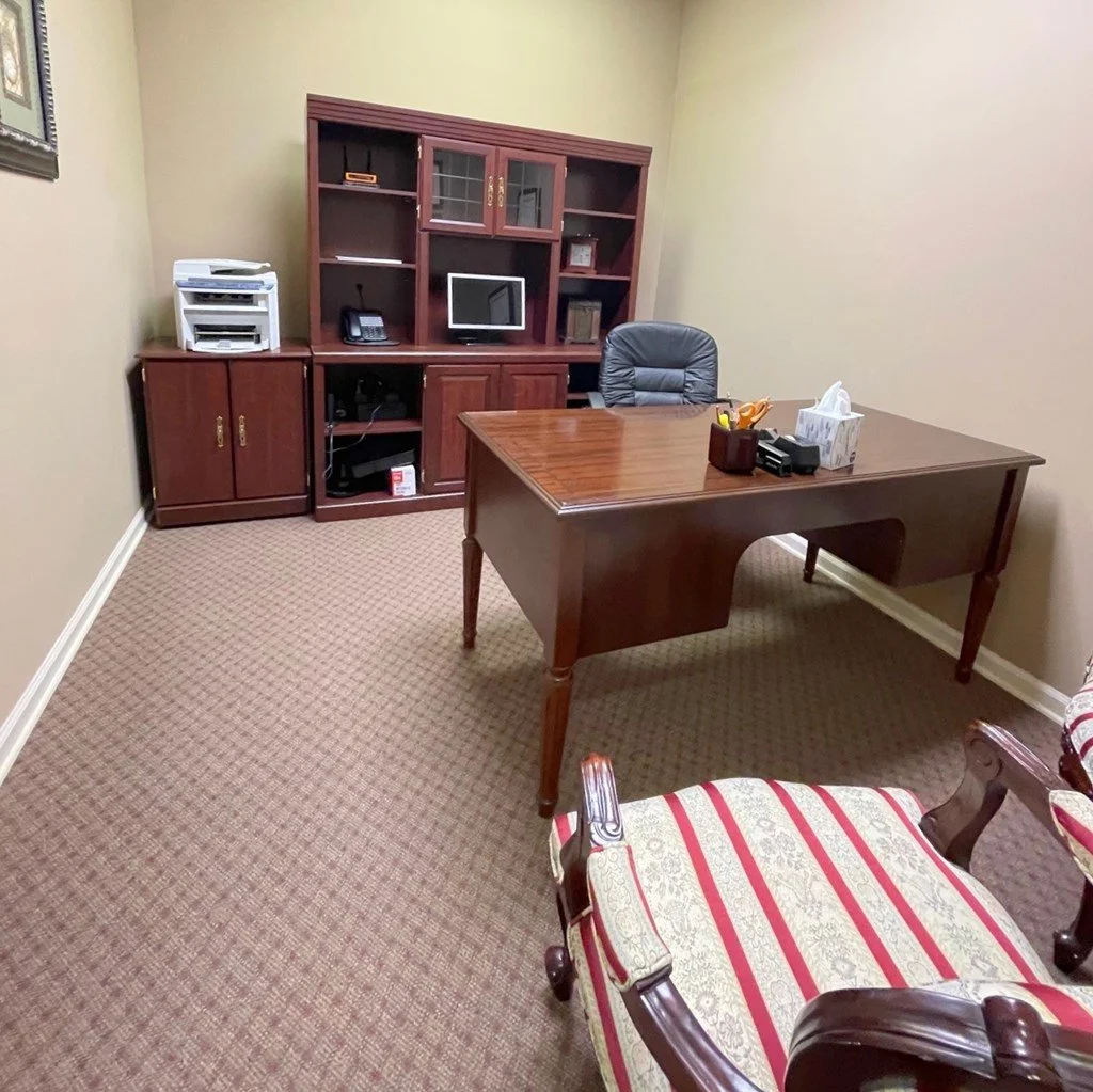 An office with a traditional mahogany finish wooden desk and a matching executive hutch
