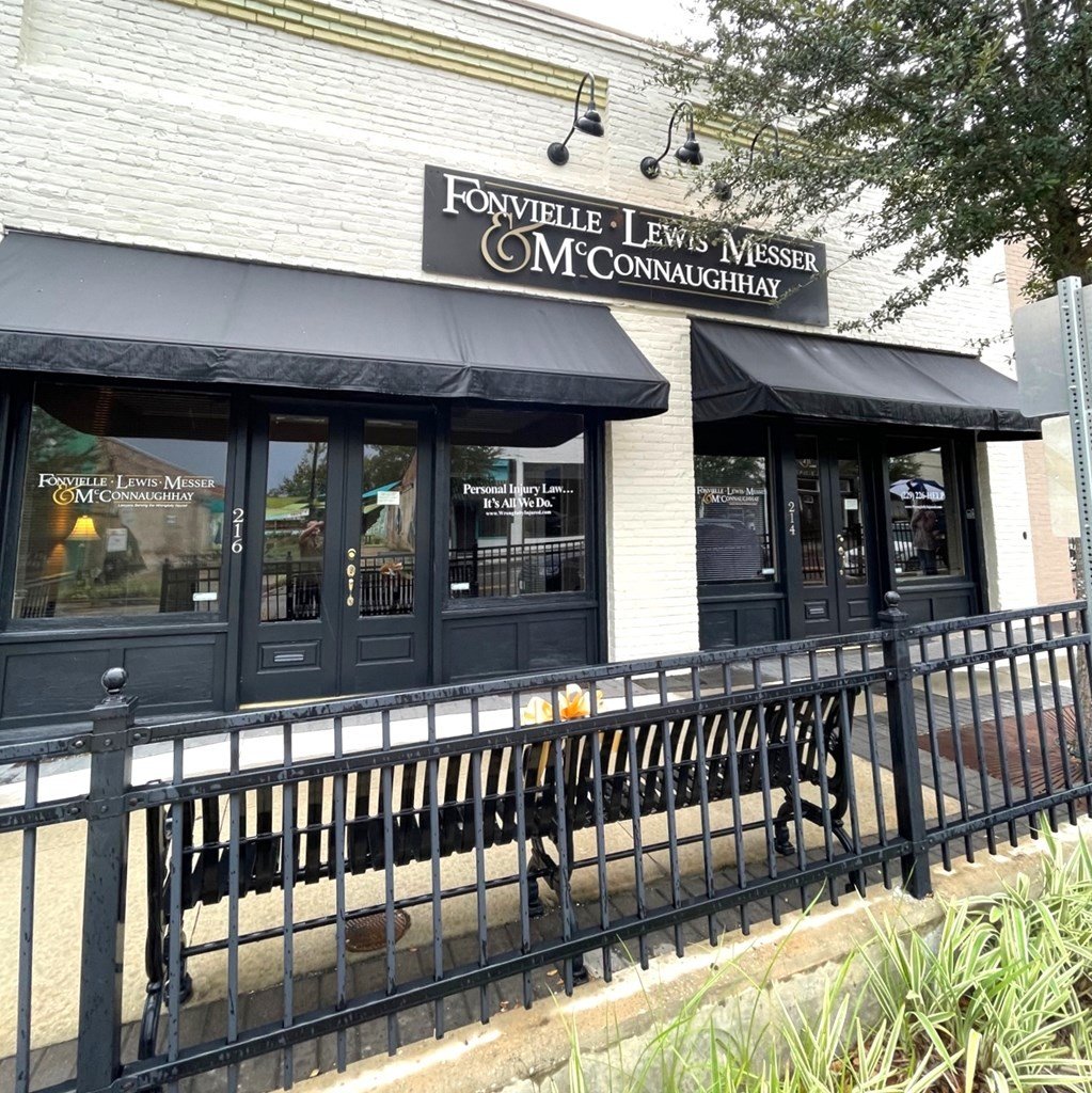 A brick law office with black awnings, a sign reading "Fonvielle Lewis Messer", and a black fence