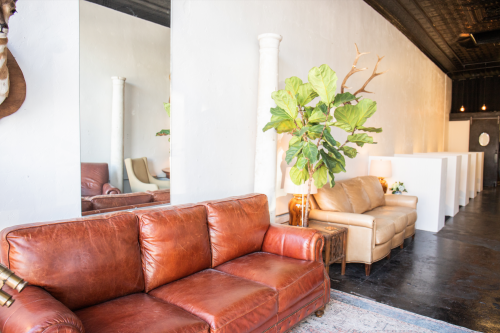 A luxurious dark tan leather sofa paired with a light-colored accent chair in the background