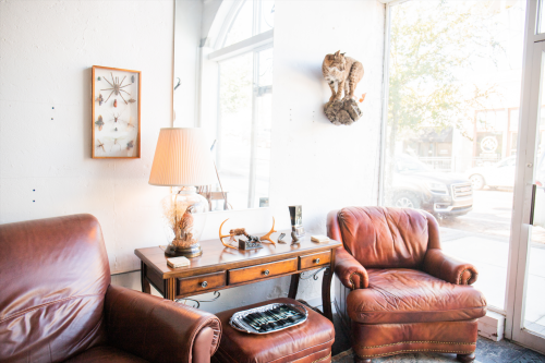 Vintage Lane leather armchairs flank a wooden console table with a lamp and decor in a bright room