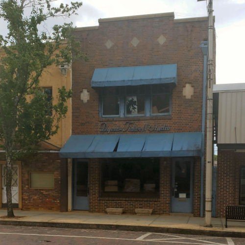 A two-story brick storefront with blue awnings over the storefront window and upper window