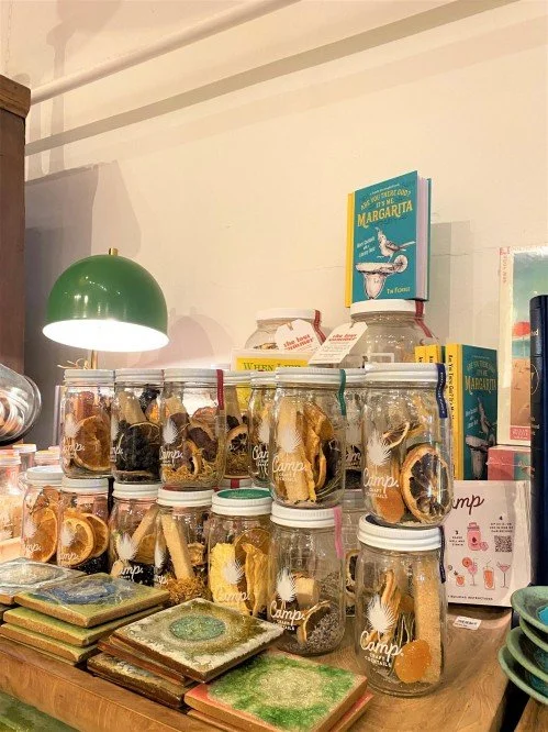Display of glass jars filled with dried citrus slices on a wooden table inside a store