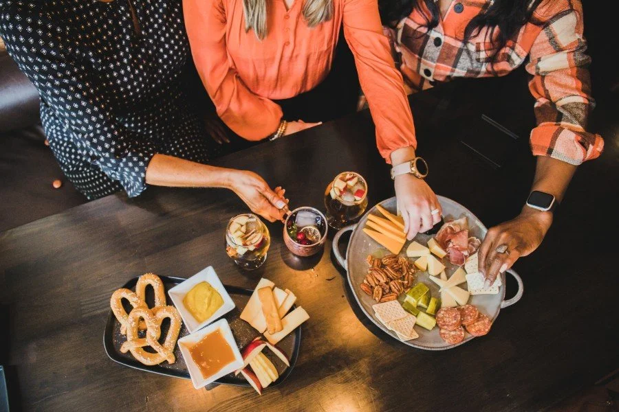 a group of people enjoying a charcuterie board and pretzels