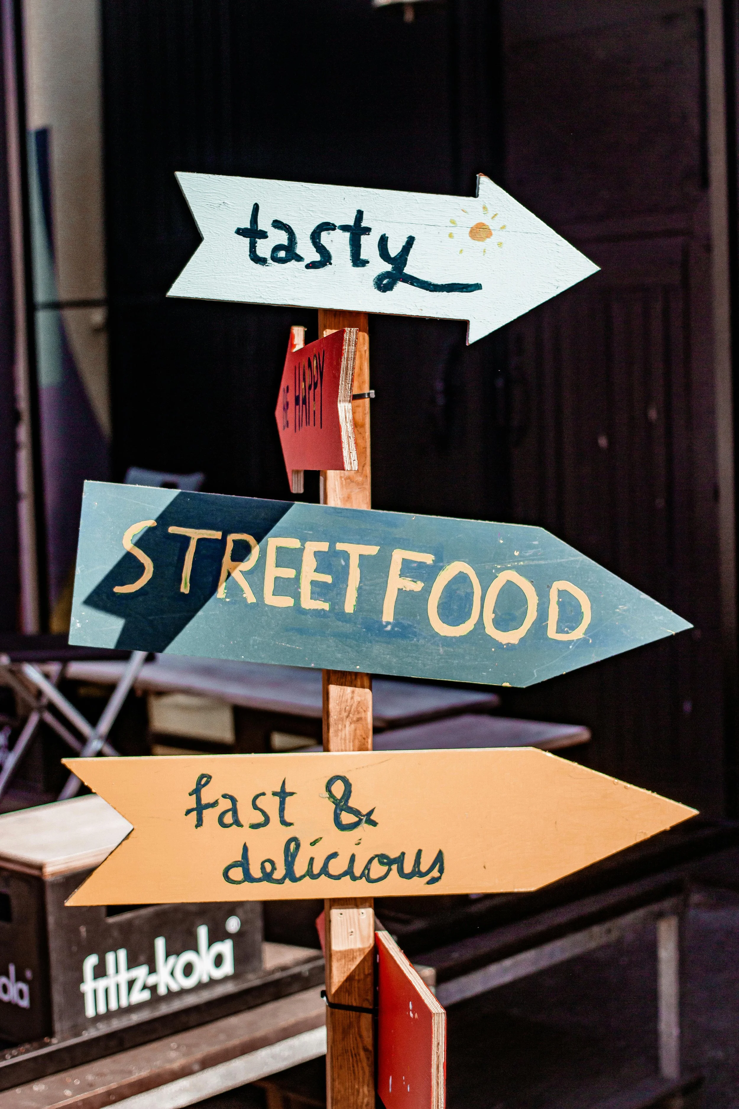 Colorful directional signs pointing to street food and fast food options at an outdoor event