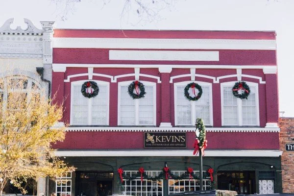 A festive decorated brick building with holiday wreaths and red bows