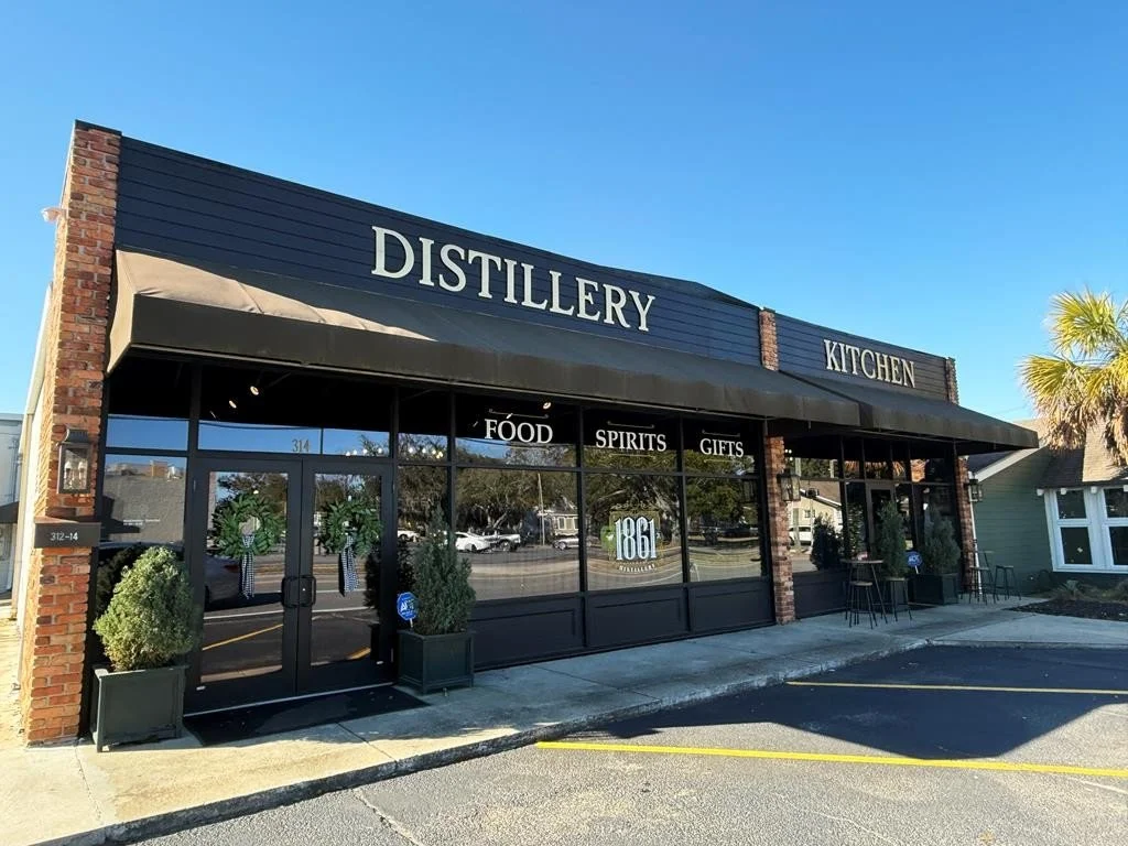 Exterior of 1861 Distillery and Kitchen storefront with dark siding and brick pillars