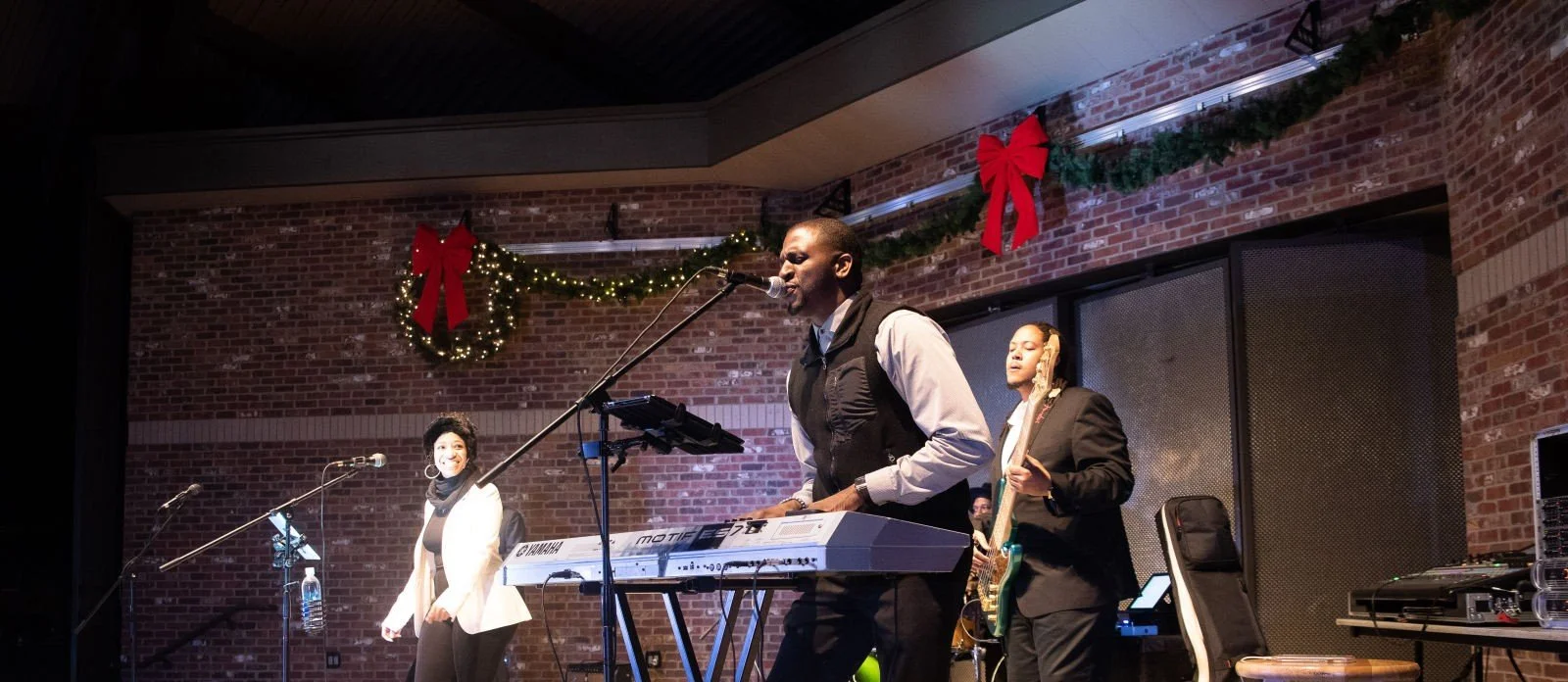 A band performing on stage decorated with holiday greenery and red bows