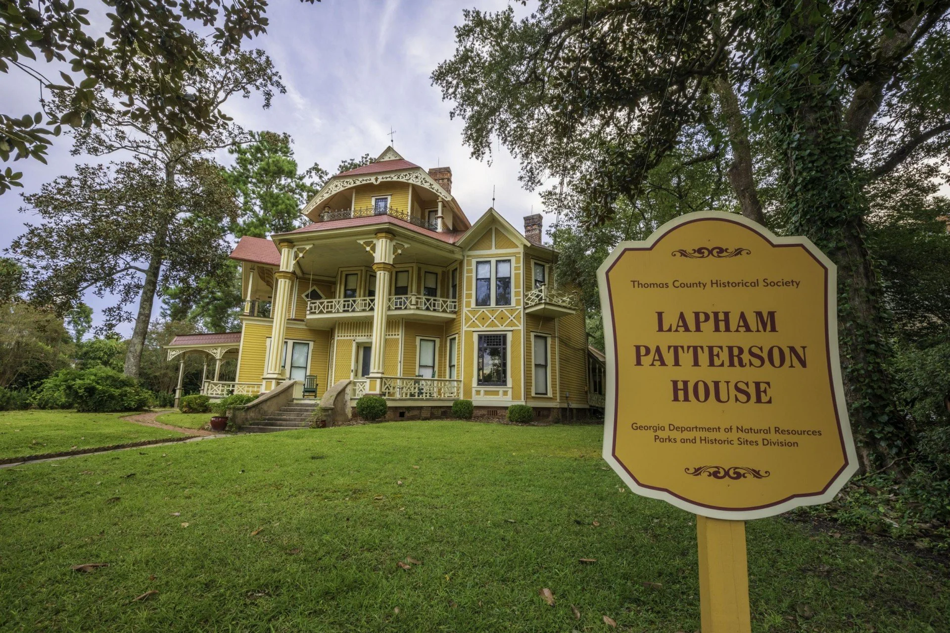 The Lapham Patterson House, a bright yellow two-story Victorian with a porch, columns, and a turret