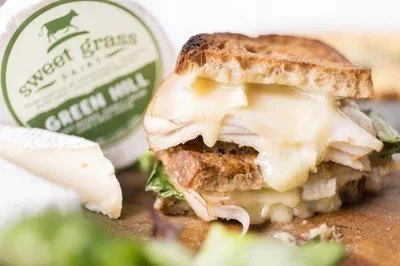 A close-up of a chicken and cheese sandwich with melted cheese, lettuce, and a toasted bun