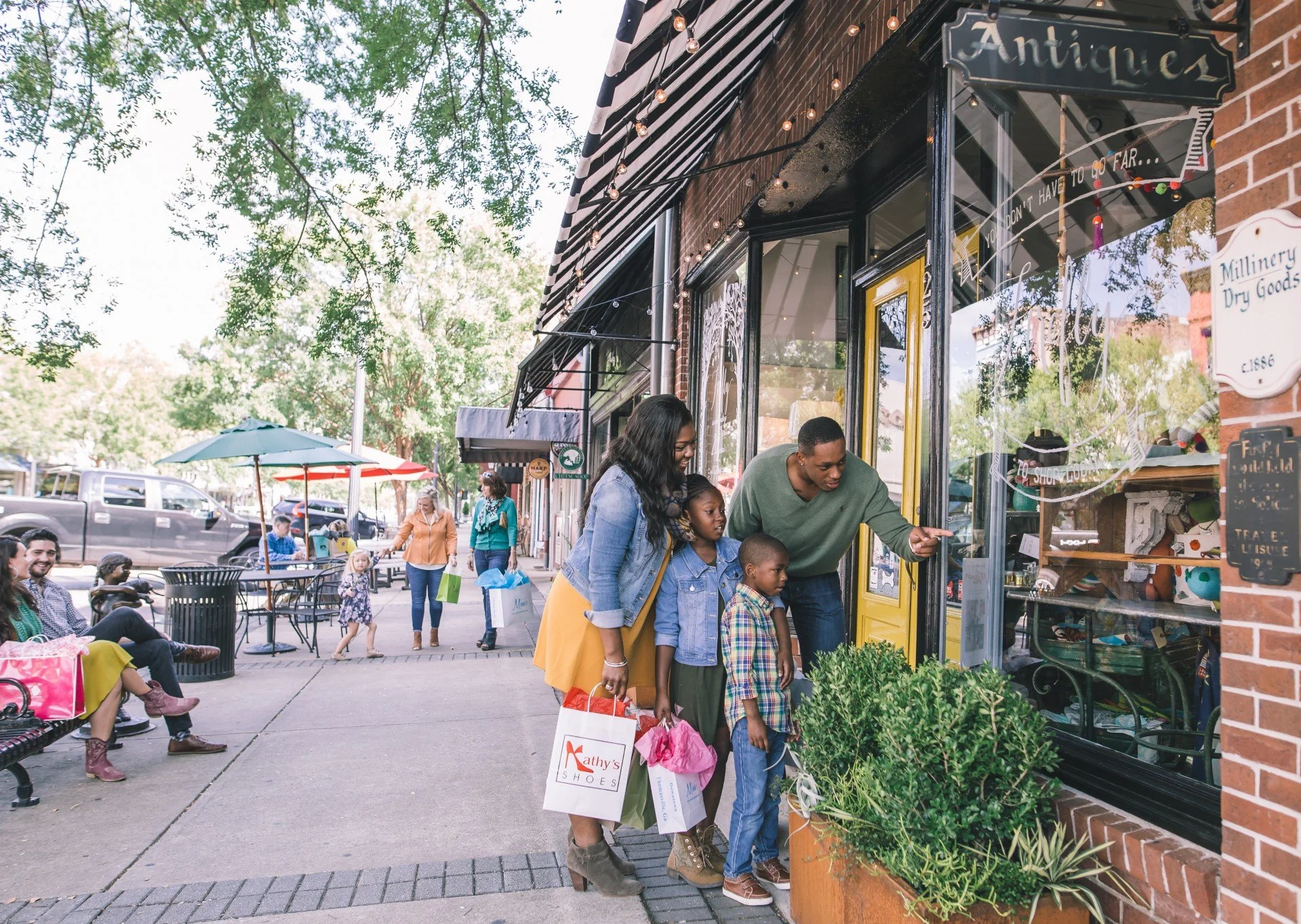 A family browsing outside local antique shops on a sunny town sidewalk