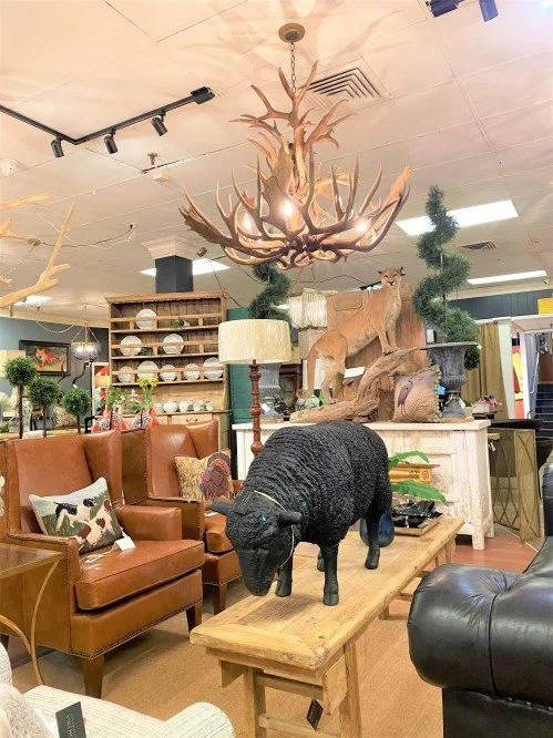 Interior of a store selling animal sculptures, a chandelier made of antlers, and greenery.