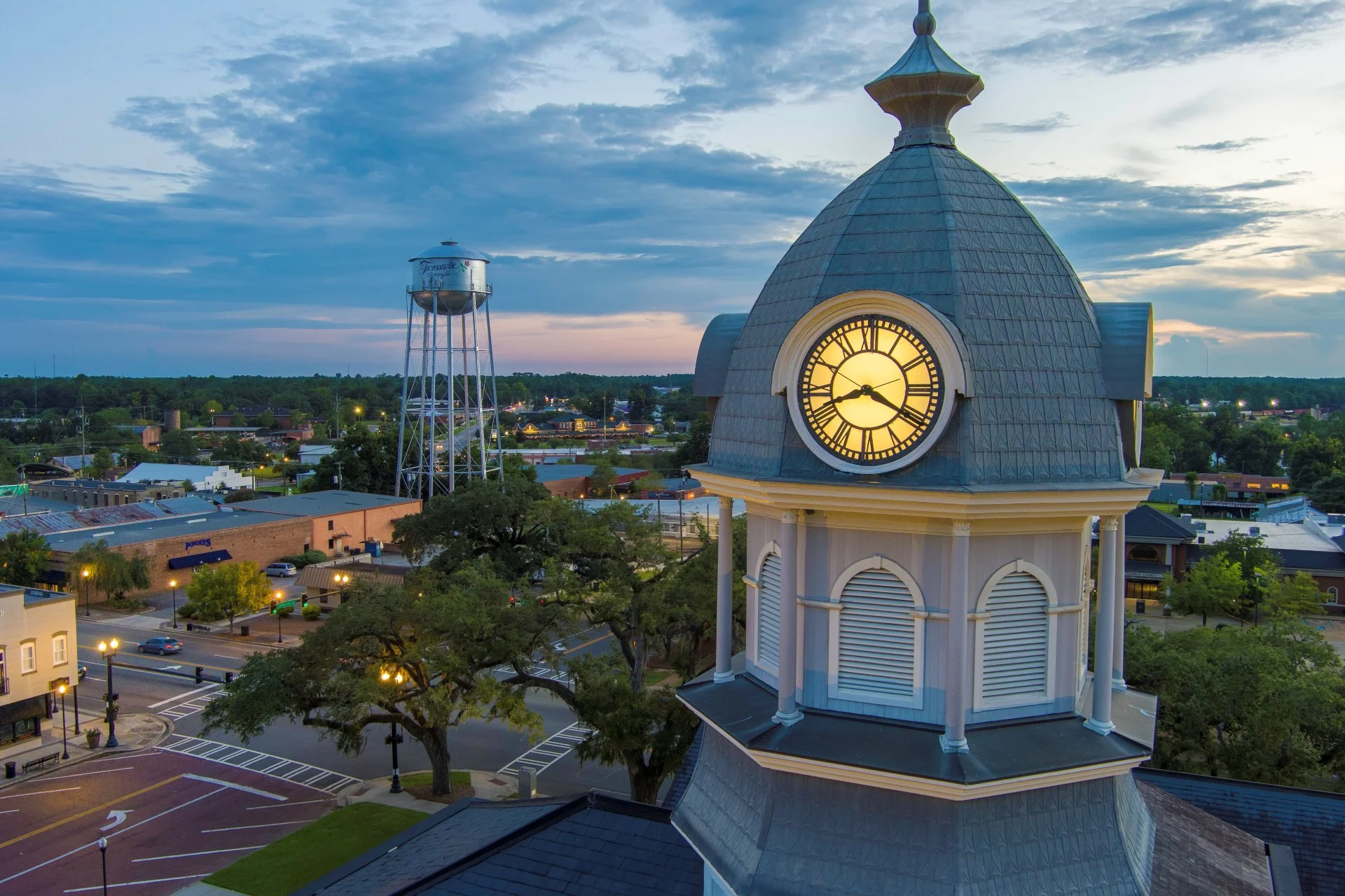 Historic town square clock tower at dusk with a water tower in the background