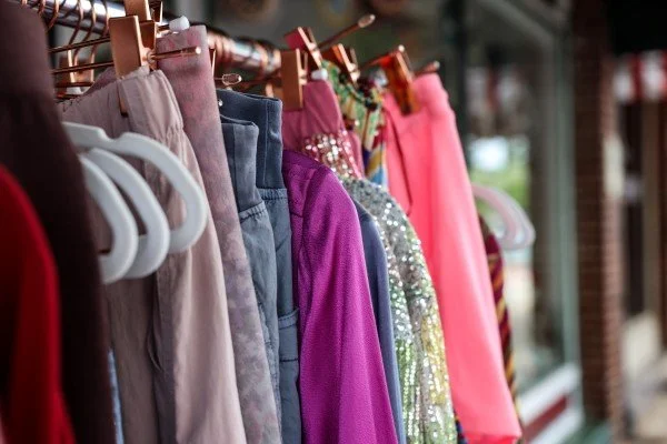 a row of colorful garments hanging on a rack at an outdoor sale