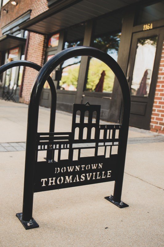 A black metal downtown Thomasville sign with the city's skyline silhouette