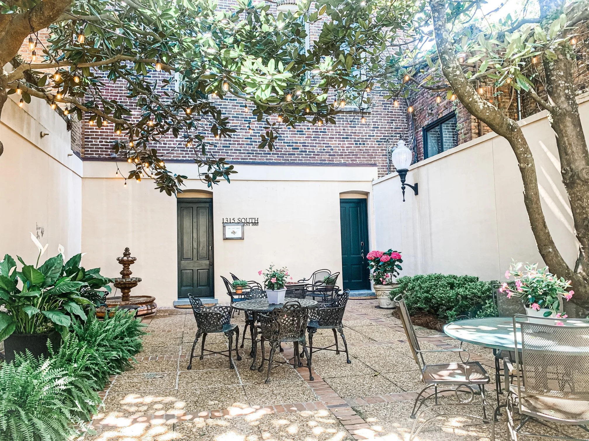 Coquettish brick courtyard filled with patio tables, potted plants, and green vines