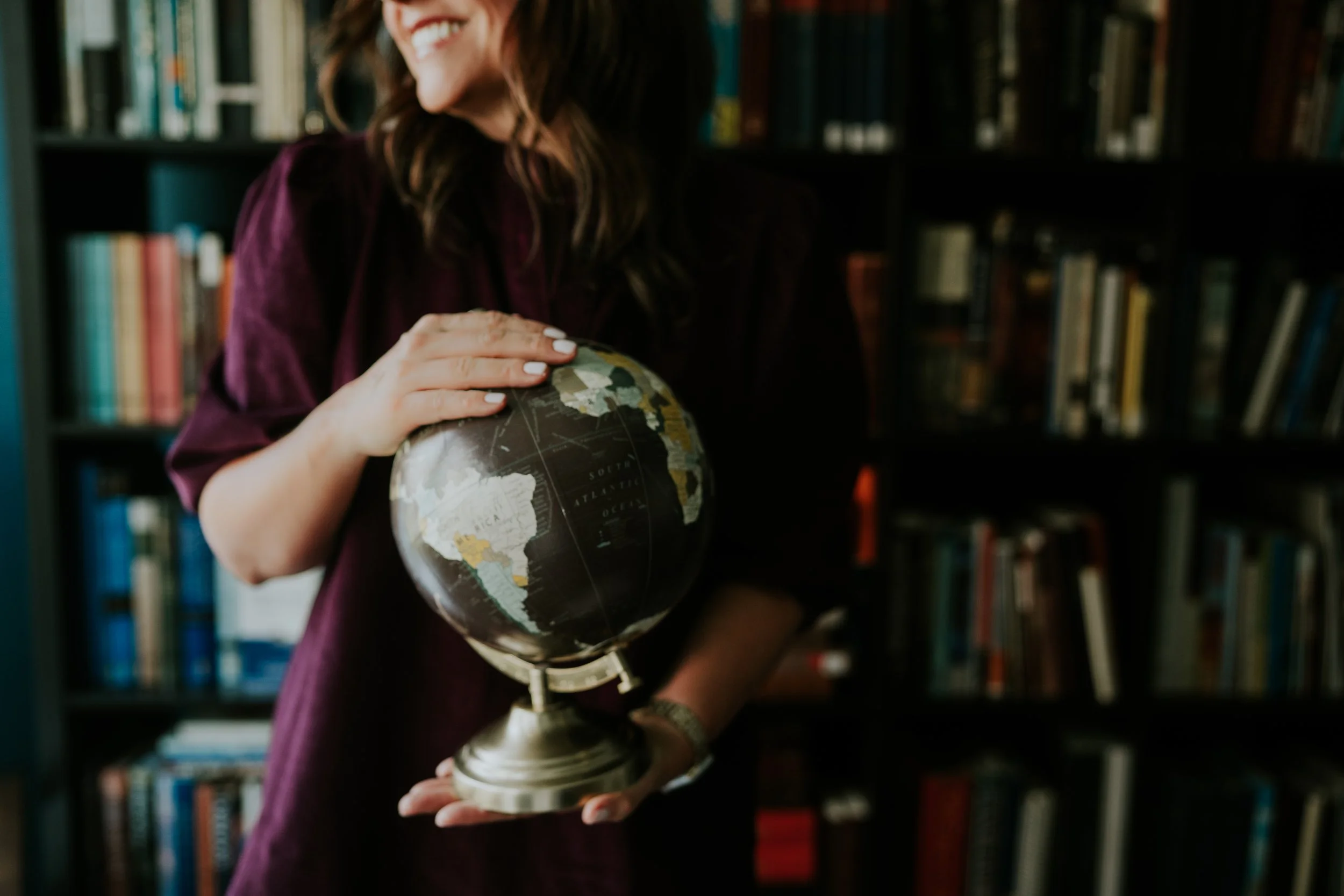 Nicole Davis holding the globe, ready to plan your worldwide travel.