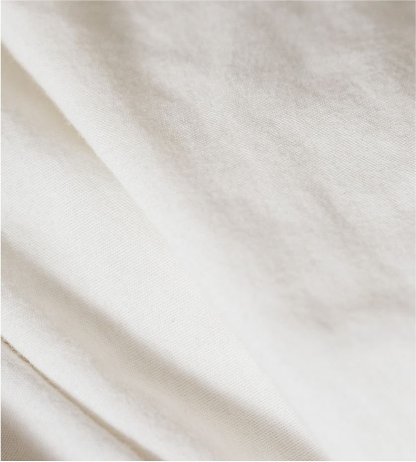 Close-up of cream-colored fabric with a smooth texture and slight sheen.