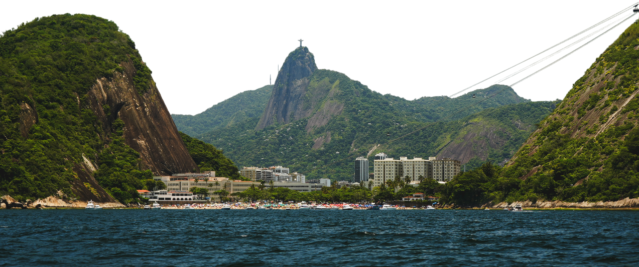 Vista da Baía de Botafogo com o Pão de Açúcar ao fundo, cercada por montanhas verdes, com um hotel e barcos na água.